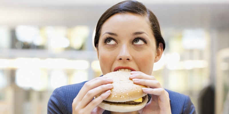 Businesswoman eating hamburger at desk in office